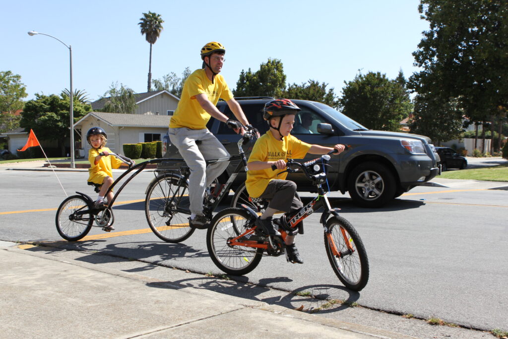 Foto de padre andando en bicicleta con sus hijos